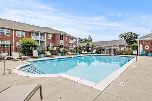 A swimming pool surrounded by a fence and chairs.