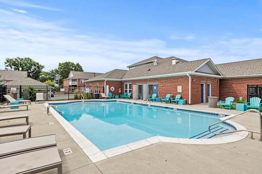 A large outdoor swimming pool with lounge chairs and a building in the background.