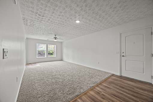 A room with a ceiling fan and a window with a view of a garden.