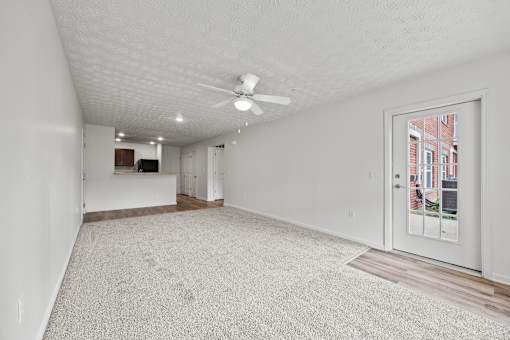 A spacious room with a ceiling fan and a door leading to a balcony.