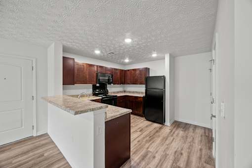 A kitchen with a black refrigerator and brown cabinets.