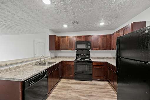 A kitchen with black appliances and wooden cabinets.