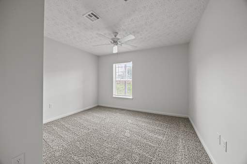 A room with a ceiling fan and carpeted floor.