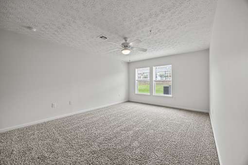 A room with a carpeted floor and a ceiling fan.
