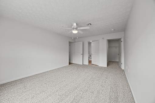 A spacious room with a ceiling fan and carpeted floor.