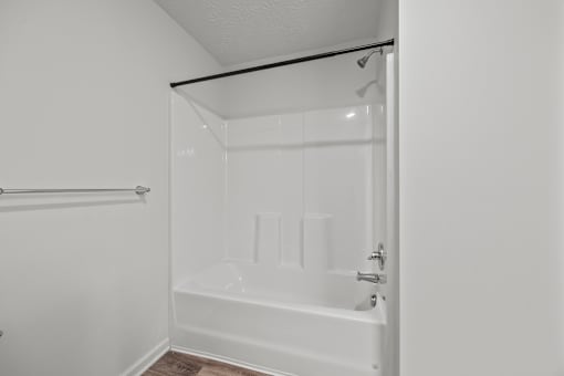A white bathroom with a bathtub and a towel rack.
