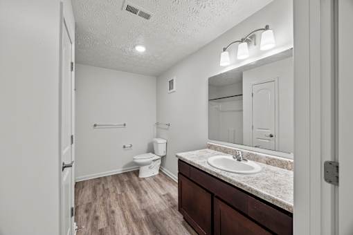A bathroom with a toilet, sink, and mirror.