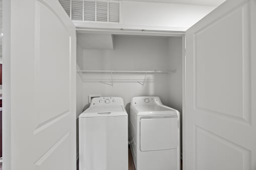 Two white washing machines in a small laundry room.