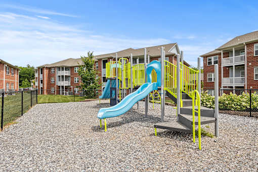 A playground with a blue slide and yellow railing.