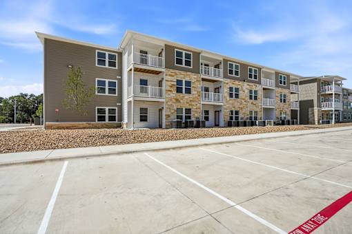A large apartment complex with a parking lot in front.