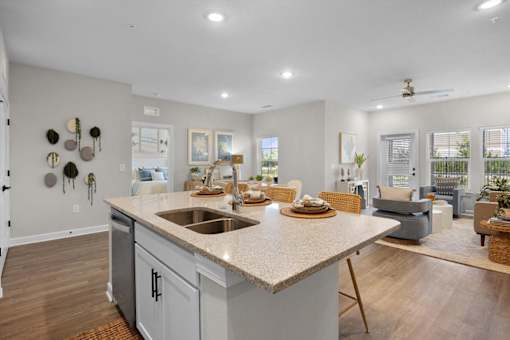A kitchen with a large island and a dining area with chairs and a table.