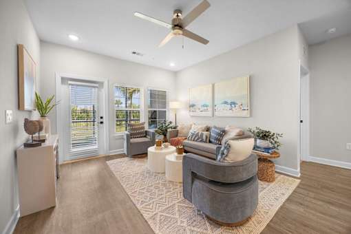 A living room with a grey couch and a painting on the wall.
