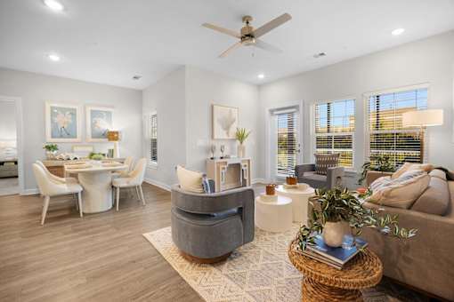 A living room with a grey couch, a white dining table, and a ceiling fan.