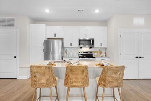 A kitchen with white cabinets and a stainless steel refrigerator.