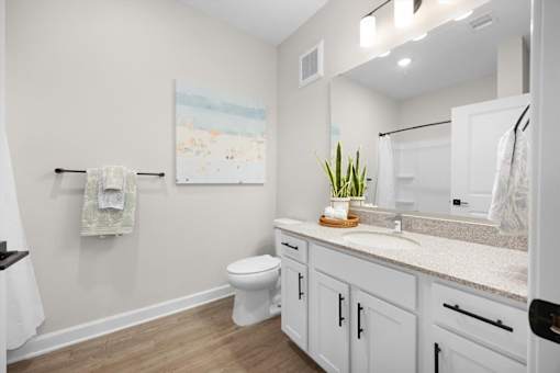 A bathroom with a toilet, sink, and a painting on the wall.