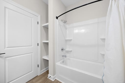 A white bathroom with a tub and a door.