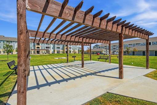A wooden pergola structure is over a concrete walkway.