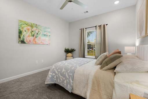 A bedroom with a large bed and a painting of flamingos on the wall.
