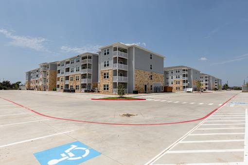 A parking lot with a handicap parking space in front of apartment buildings.