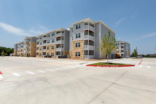 A large apartment complex with a parking lot in front.
