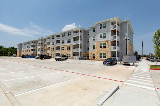 A parking lot in front of a multi-story apartment building.