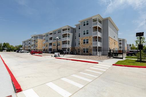 A large apartment complex with a parking lot in front.