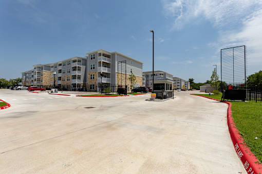 A parking lot in front of a multi-story apartment building.