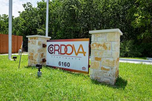 A sign for ERDOVA APARTMENTS stands in front of a stone pillar.
