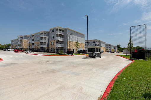 A parking lot in front of a multi-story apartment building.