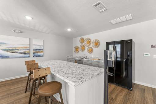 A kitchen with a marble countertop and a fridge.