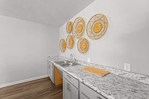 A kitchen with a marble countertop and wooden cabinets.
