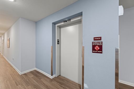A hallway with a sign on the wall that says "Elevator".