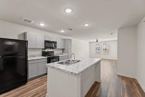 A kitchen with a black refrigerator and white countertops.