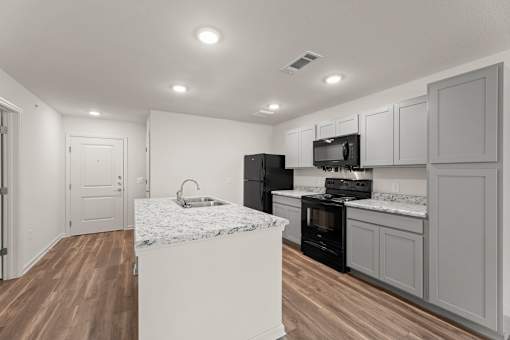 A kitchen with a white marble island and dark wood floors.