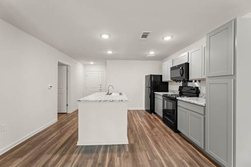 A kitchen with a white island and black appliances.
