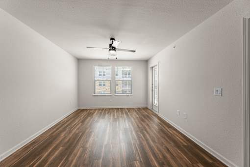 A room with a ceiling fan and wooden flooring.