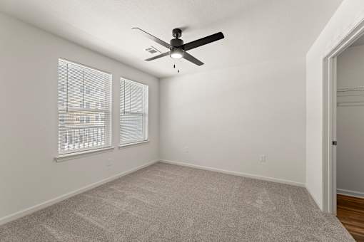 A room with a ceiling fan and carpeted floor.