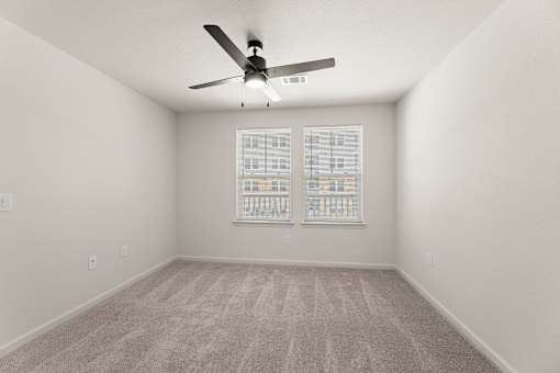 A room with a ceiling fan and carpeted floor.