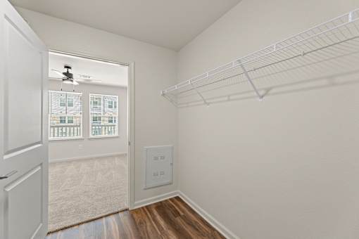 A white closet with a doorway leading to a balcony.