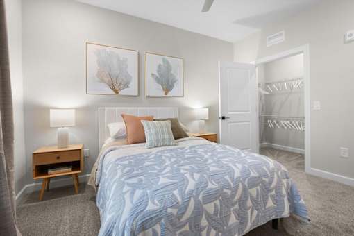 A bedroom with a bed, nightstand, and two framed pictures on the wall.