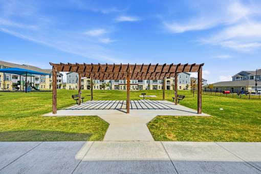 A wooden pergola is in the middle of a grassy area.