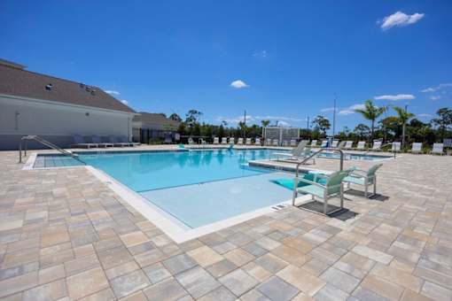 A large outdoor swimming pool surrounded by a brick patio.