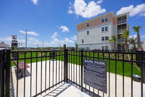 A sign in front of a fence reads Bark Park.
