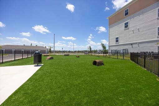 A grassy area in front of a building with a black fence.