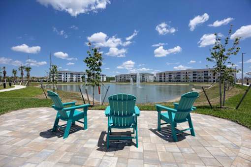 Three green chairs are arranged in a circle on a patio.