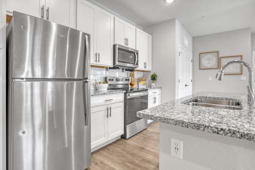 A modern kitchen with a stainless steel refrigerator and granite countertops.