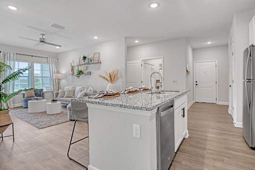 A modern kitchen with a marble countertop and a refrigerator on the right.