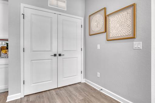 A white door with a black handle and a white wall with two framed pictures on it.