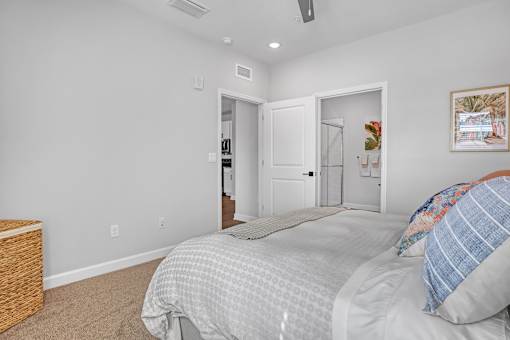A bedroom with a bed, pillow, and a picture on the wall.