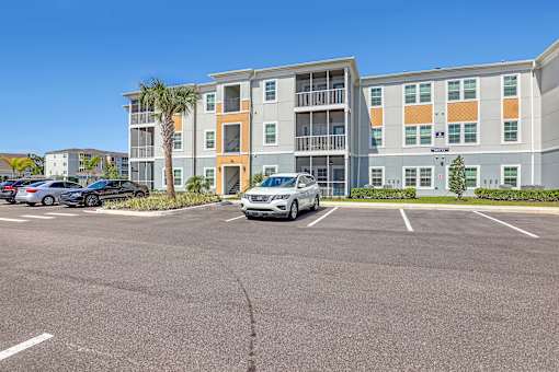 A parking lot in front of a multi-story apartment building.